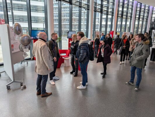 Bild der Lounge und des Parkour-Bereichs. Viele Personen nutzen die Angebote des Parkour-Bereichs, um sich über digitale Barrierefreiheit zu informieren.