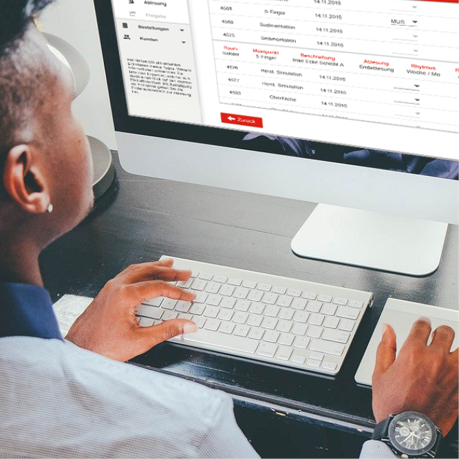 Nahaufnahme einer Person an einem Arbeitsplatz mit Monitor und Tastatur. Der Person wird über die Schulter geschaut, während mit dem neuen U I Design des digitalisierten Probenentnahmeprozesses gearbeitet wird.